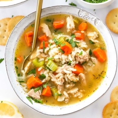 A bowl with leftover turkey rice soup garnished with parsley.