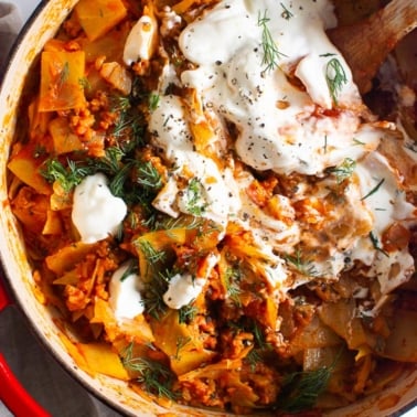 Unstuffed cabbage rolls topped with greek yogurt, dill and pepper in red pot.