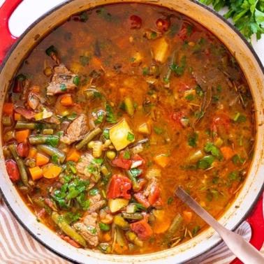 Vegetable beef soup in a pot with ladle.
