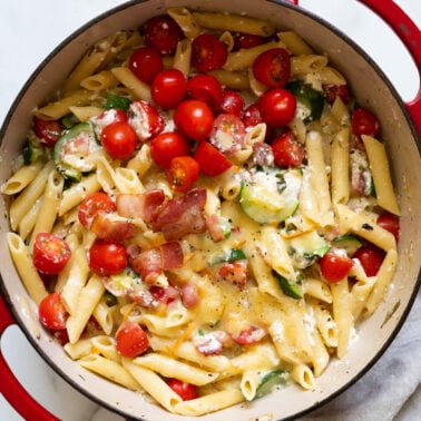 One pot zucchini ricotta pasta with bacon garnished with basil.