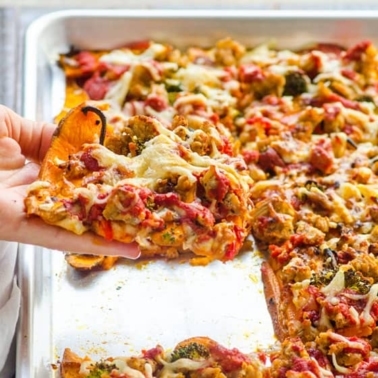 Person holding a slice of sweet potato pizza crust.