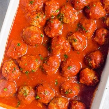 Instant Pot meatballs in sauce garnished with parsley in baking dish.