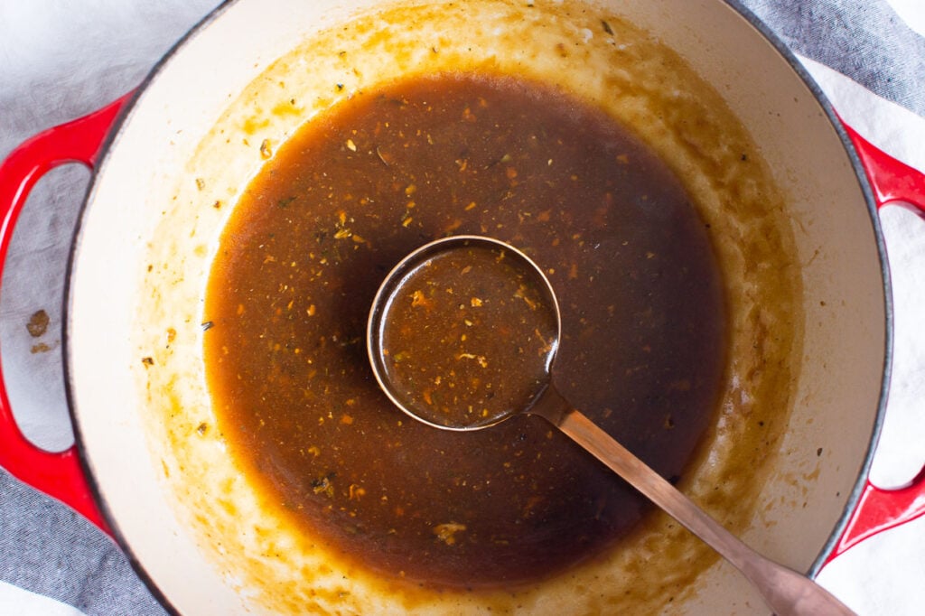 healthy turkey gravy in red pot and ladle