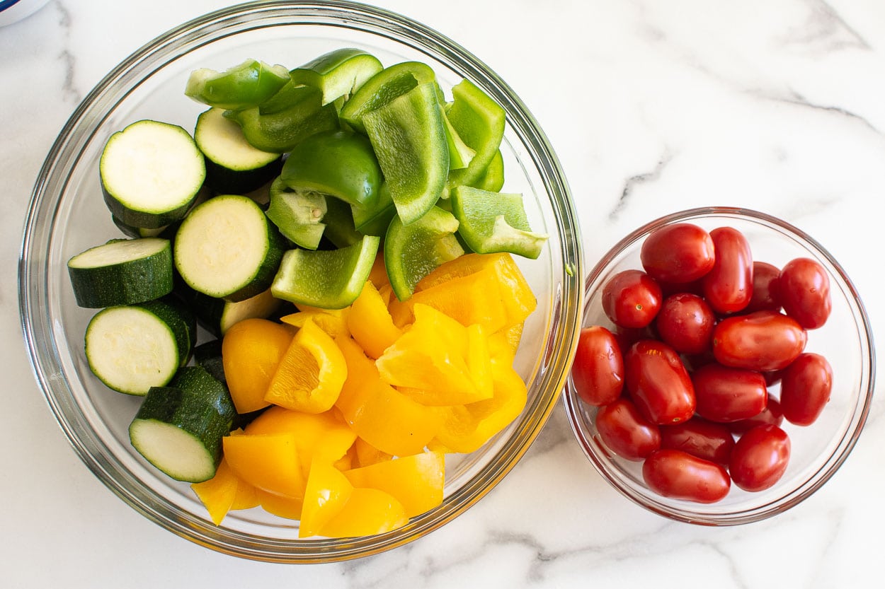 Zucchini, green and yellow pepper in one bowl. Cherry tomatoes in another bowl.