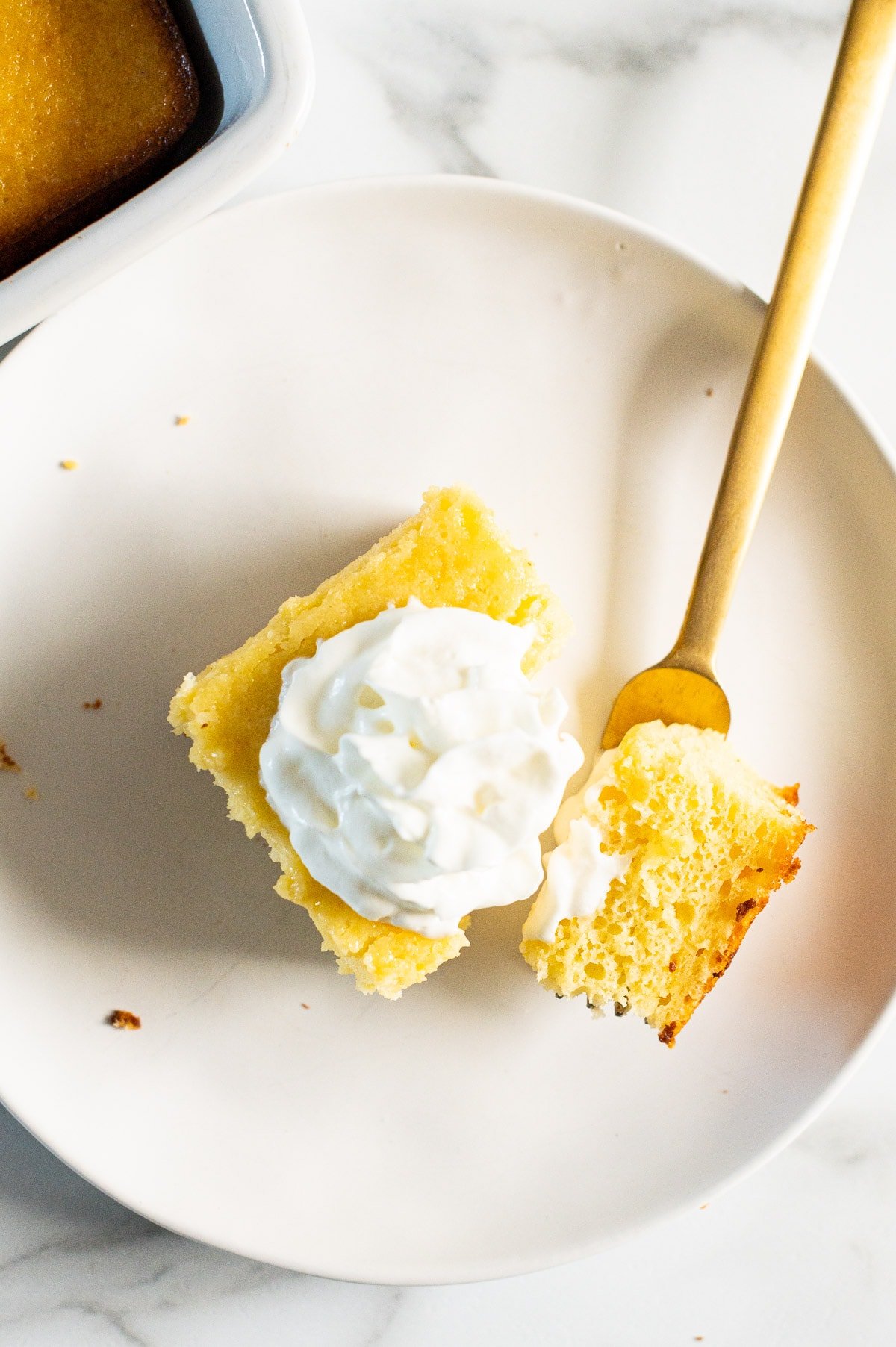 A slice of yogurt cake on a plate and fork with a small piece on it.