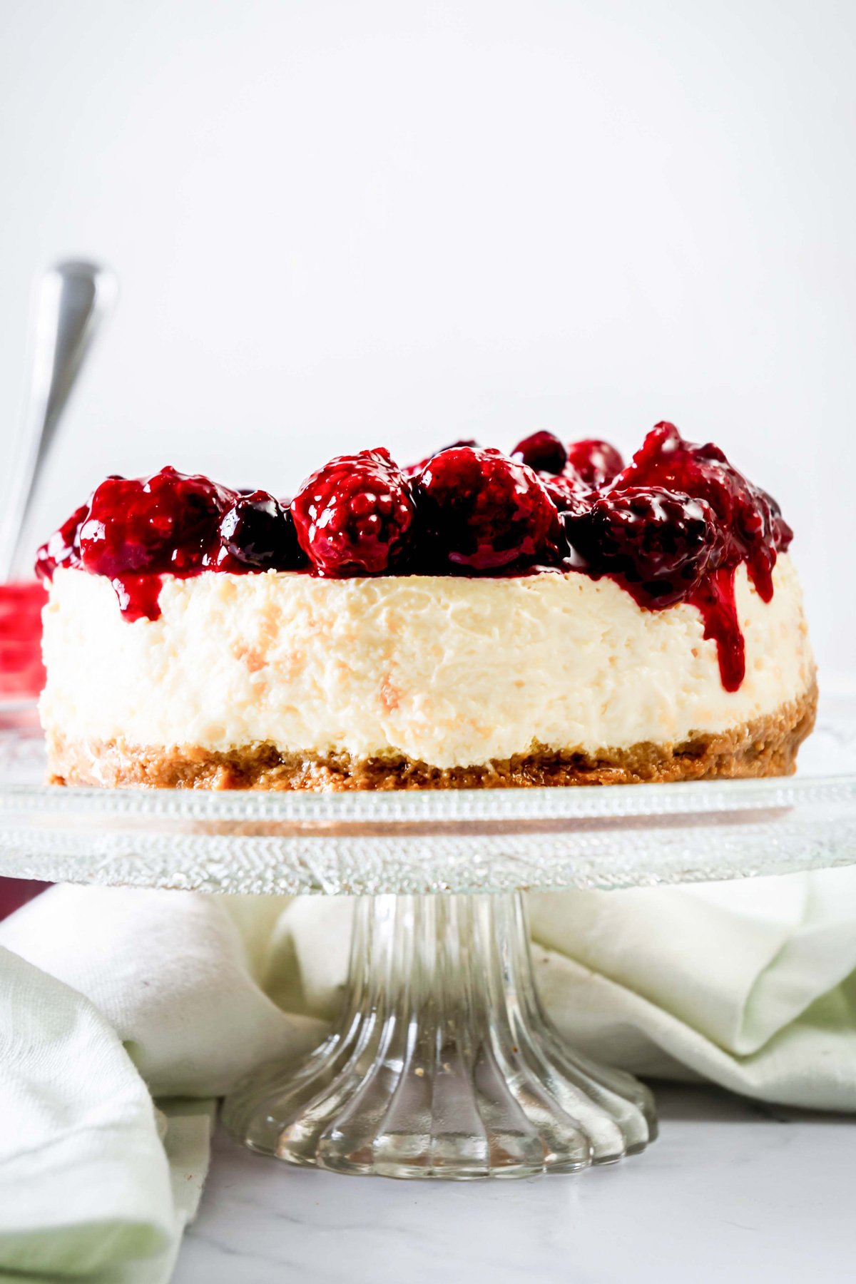 Greek yogurt cheesecake with berry compote on a cake plate.
