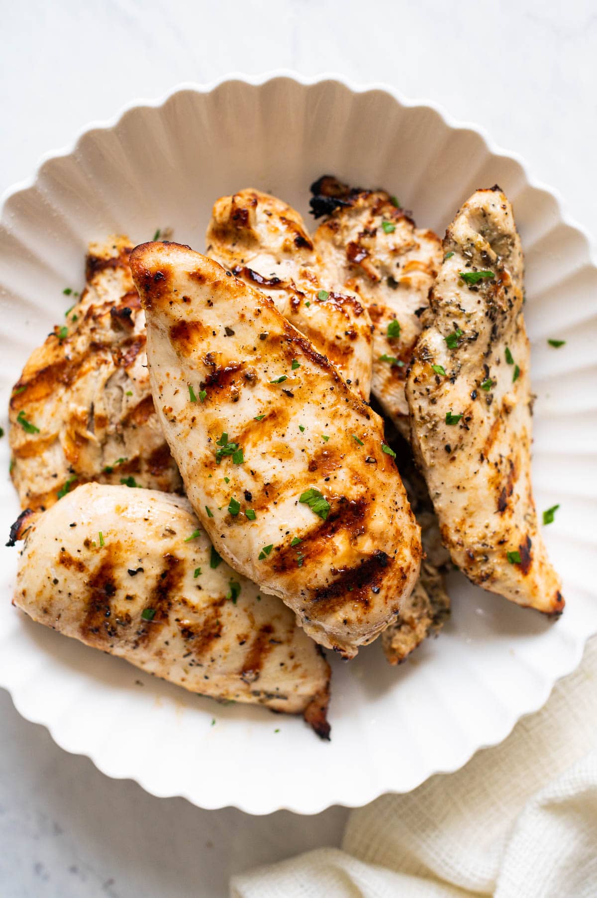 Grilled chicken breasts garnished with parsley and served on a plate.