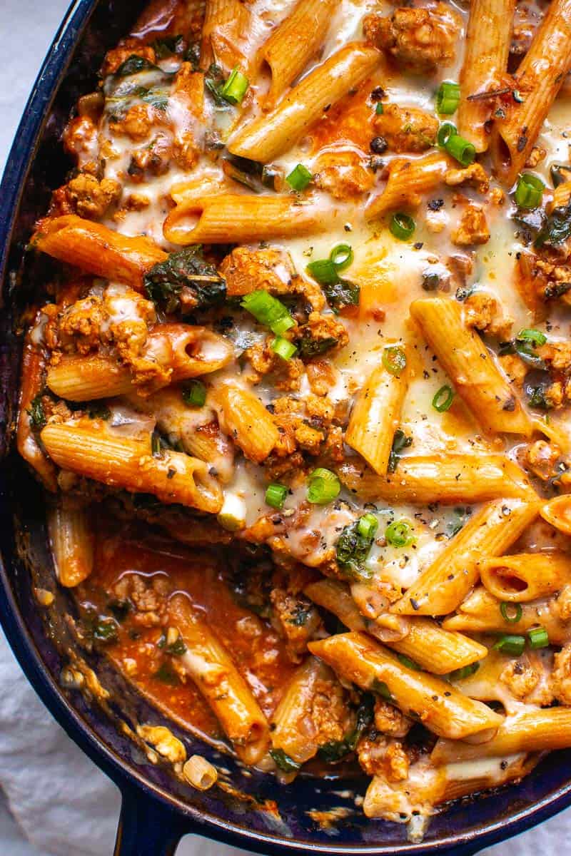 Casserole with pasta, ground turkey, melted cheese and green onions on top.