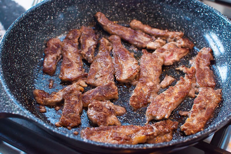 Strips of beef in skillet.
