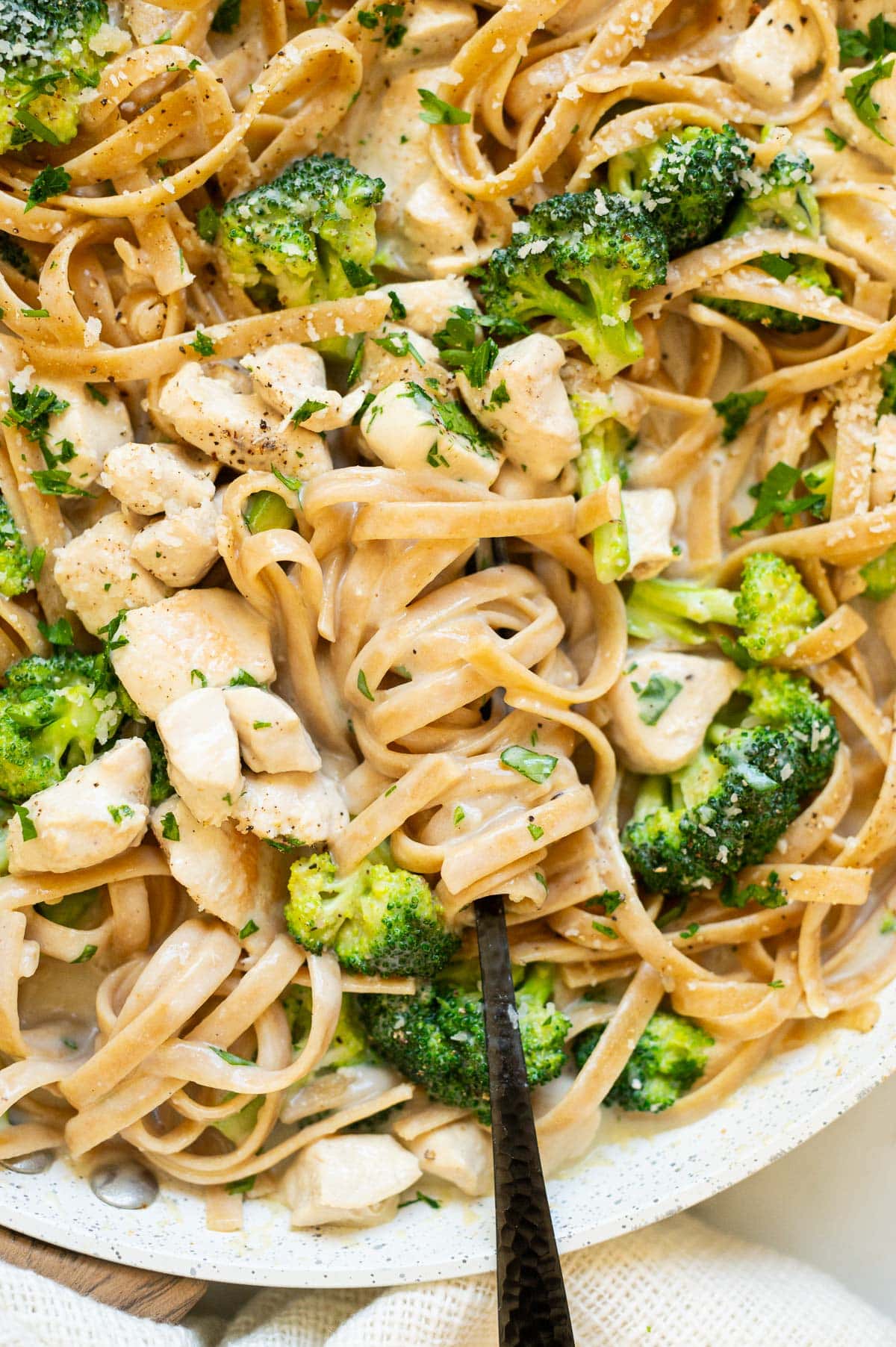 Healthy chicken alfredo with broccoli and wrapped around a fork.