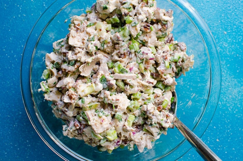 Healthy chicken salad stirred in a bowl with spoon.