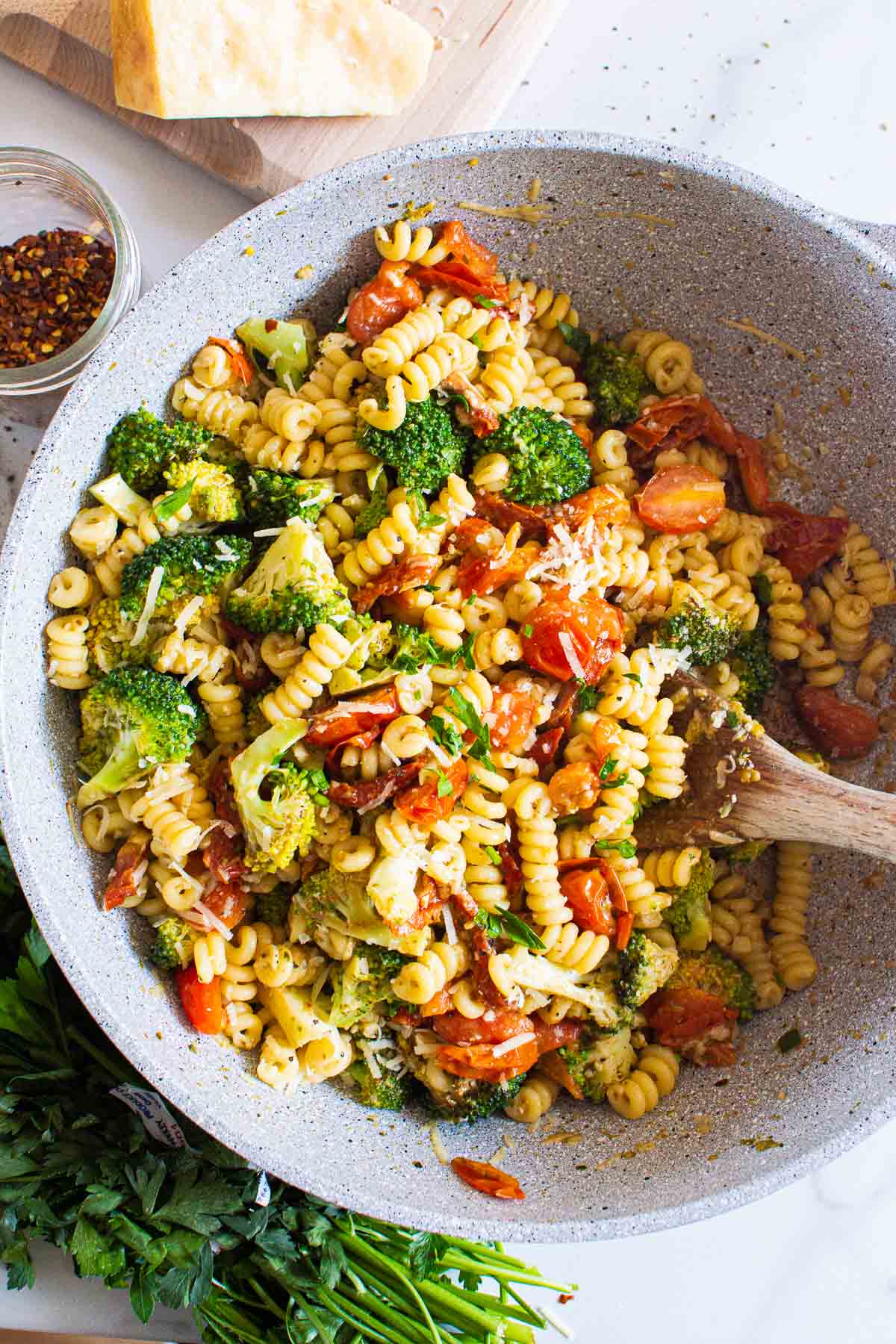 Spiral shaped pasta with broccoli in gray bowl.