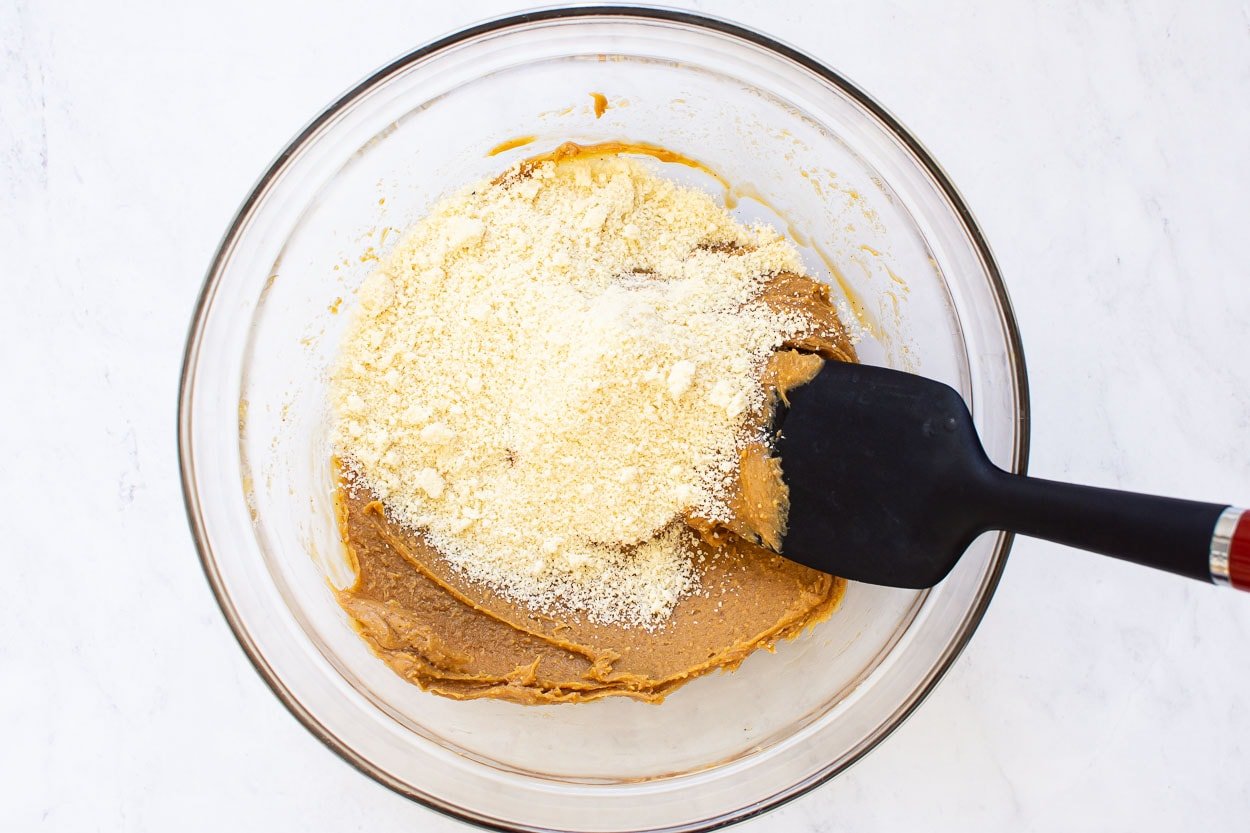 Peanut butter, maple syrup, vanilla and almond flour in glass bowl mixed.