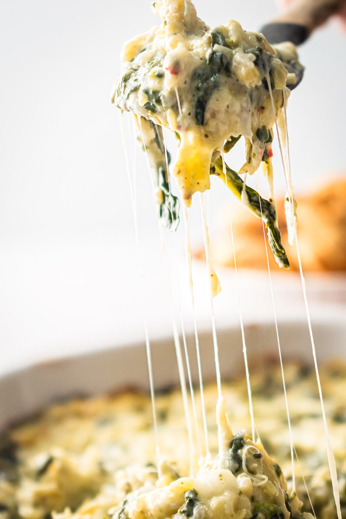 Healthy spinach artichoke dip on a spoon.