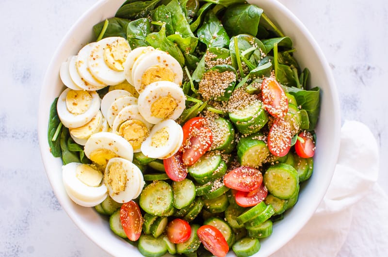 healthy spinach salad served in a large white bowl