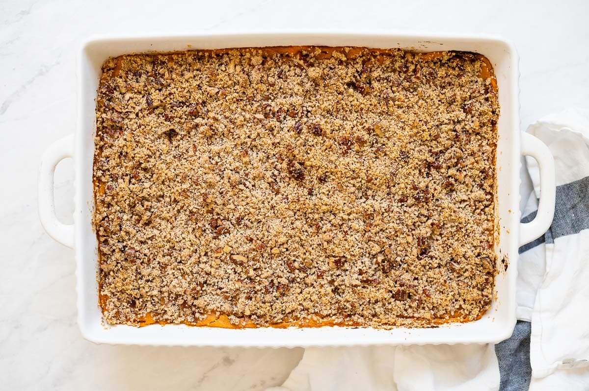 Healthy sweet potato casserole with a wooden spoon in baking dish.