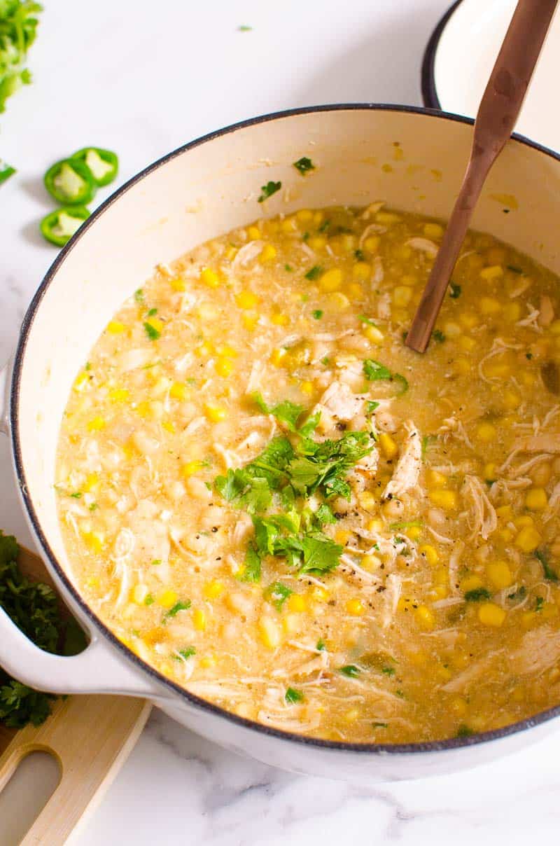 Healthy white chicken chili in white pot garnished with cilantro.