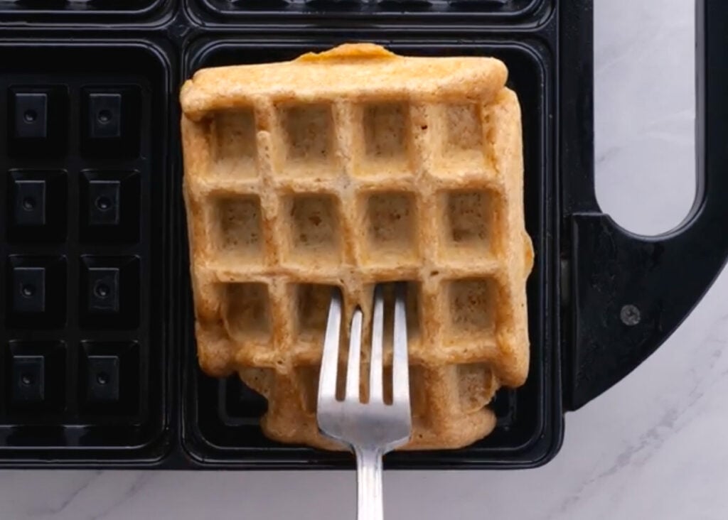 Removing waffles from the griddle with a fork.