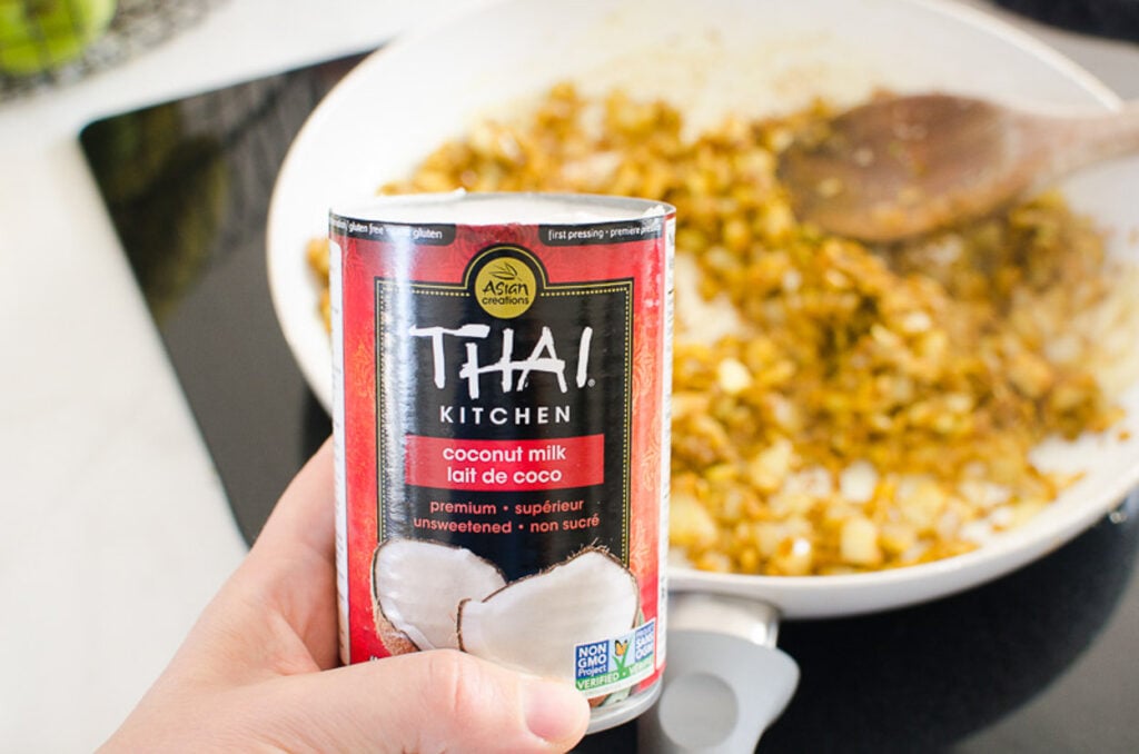Thai kitchen coconut milk with curry on stove in background.