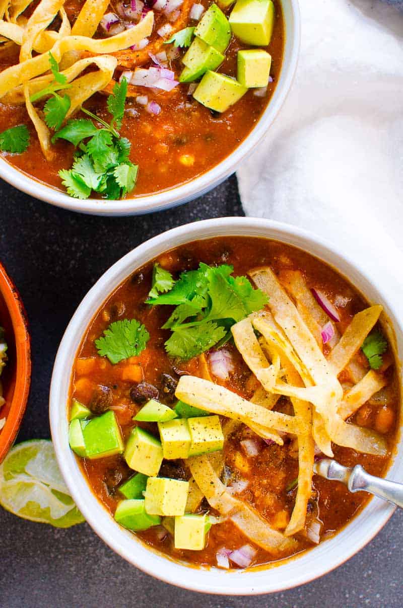 Instant Pot chicken tortilla soup garnished with tortilla strips, avocado and cilantro served in bowls.