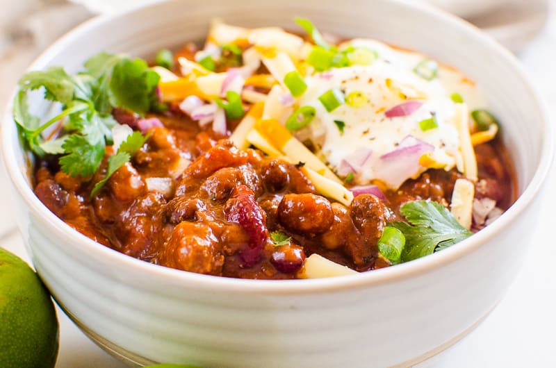 Instant pot chili garnished with red onion, cheese and cilantro in a bowl.