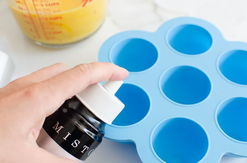 Spraying egg bit mold with cooking spray.