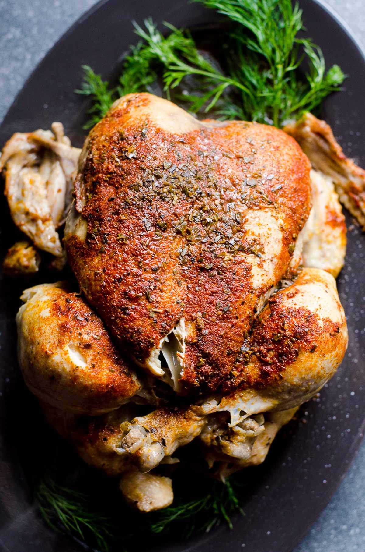 Instant Pot frozen whole chicken on a platter garnished with dill.