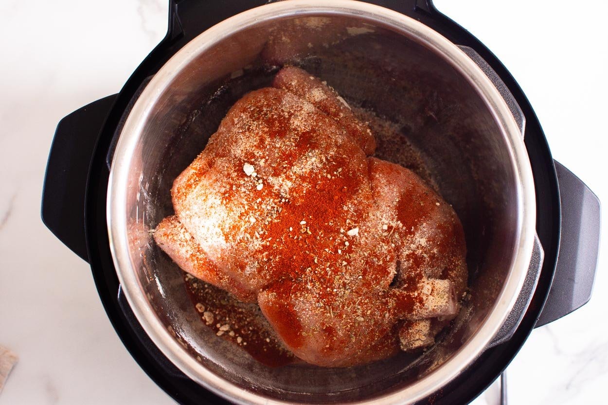 Whole chicken sprinkled with spices inside the pressure cooker.