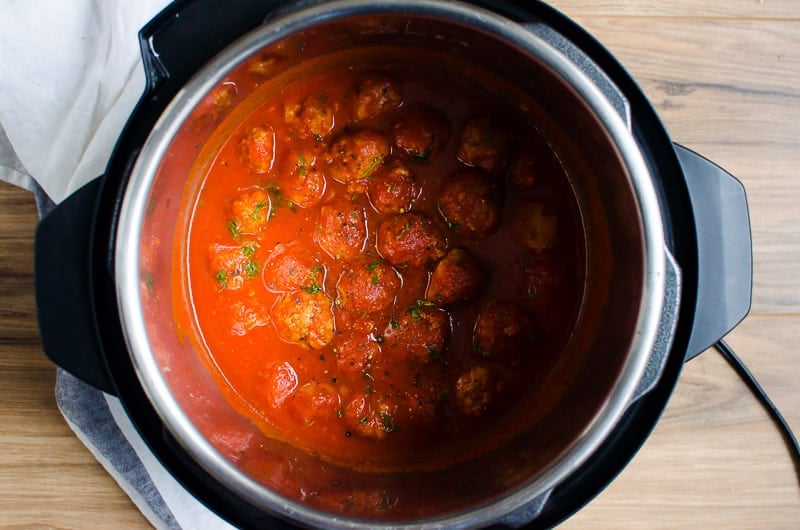Cooked Instant Pot meatballs in sauce garnished with parsley.