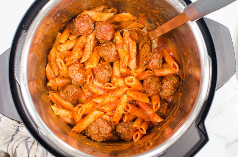 Pasta and meatballs in Instant Pot with a spoon.