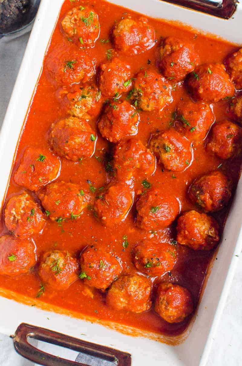 Instant Pot meatballs in sauce garnished with parsley in baking dish.