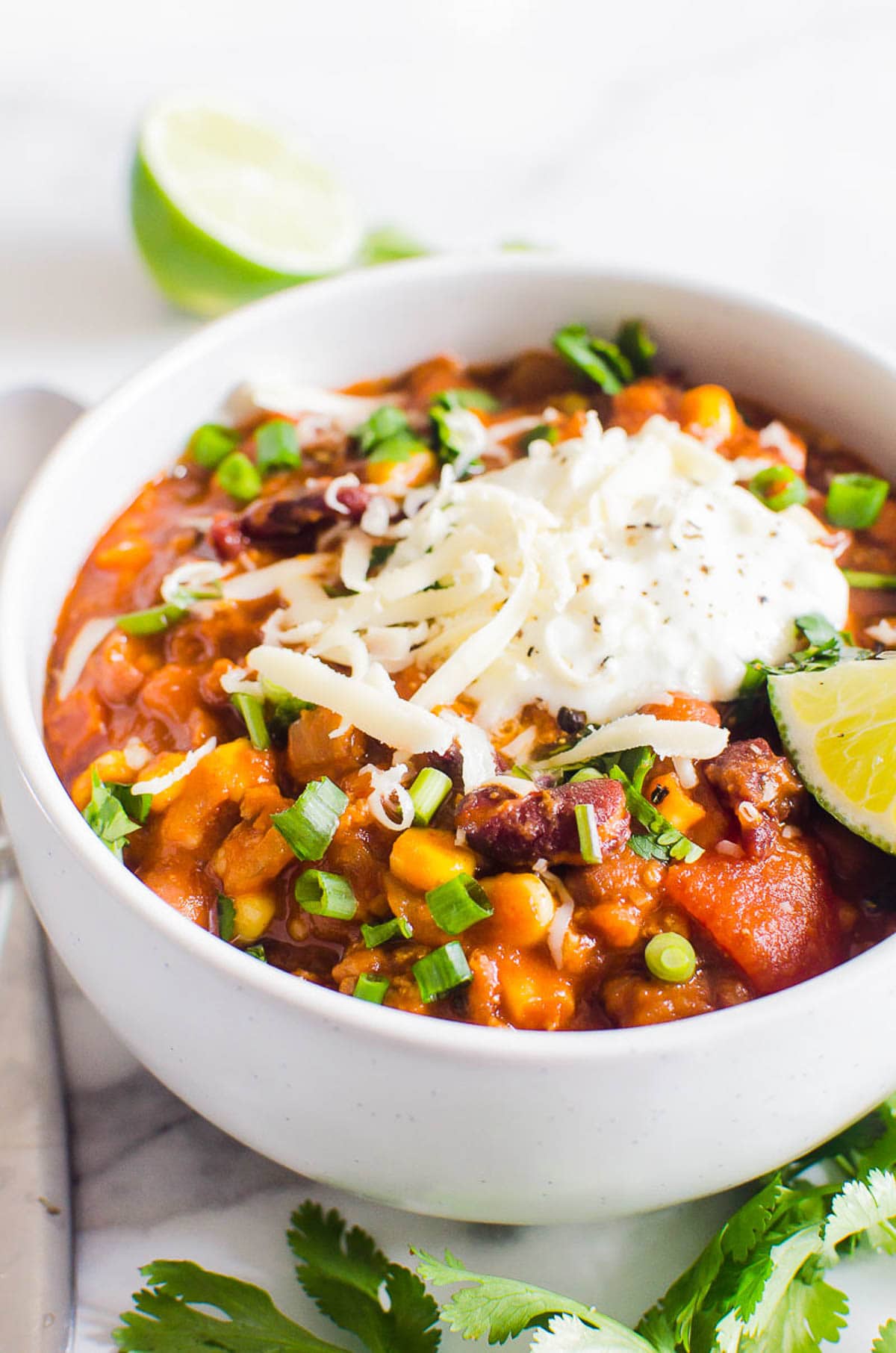 Instant Pot turkey chili garnished with sour cream, cheese and green onion in white bowl.