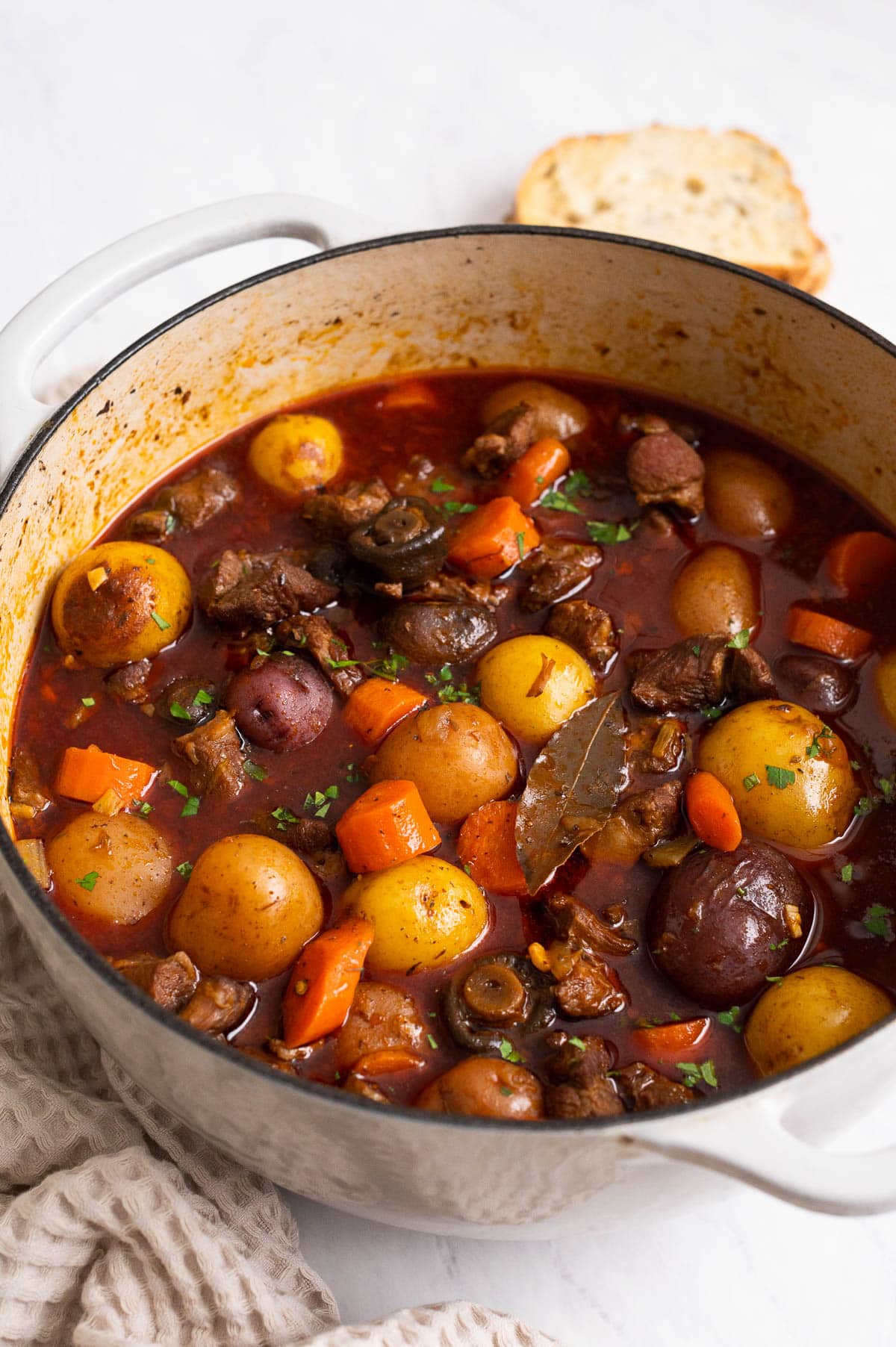 Lamb stew with carrots and potatoes in white pot.