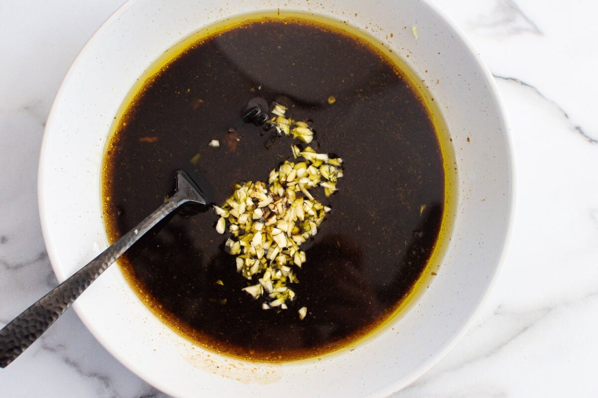 A bowl with olive oil, balsamic vinegar,  and garlic. Plus fork in it.