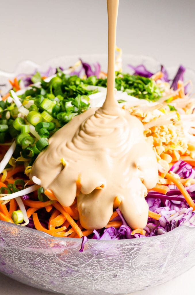 dressing being poured on peanut slaw
