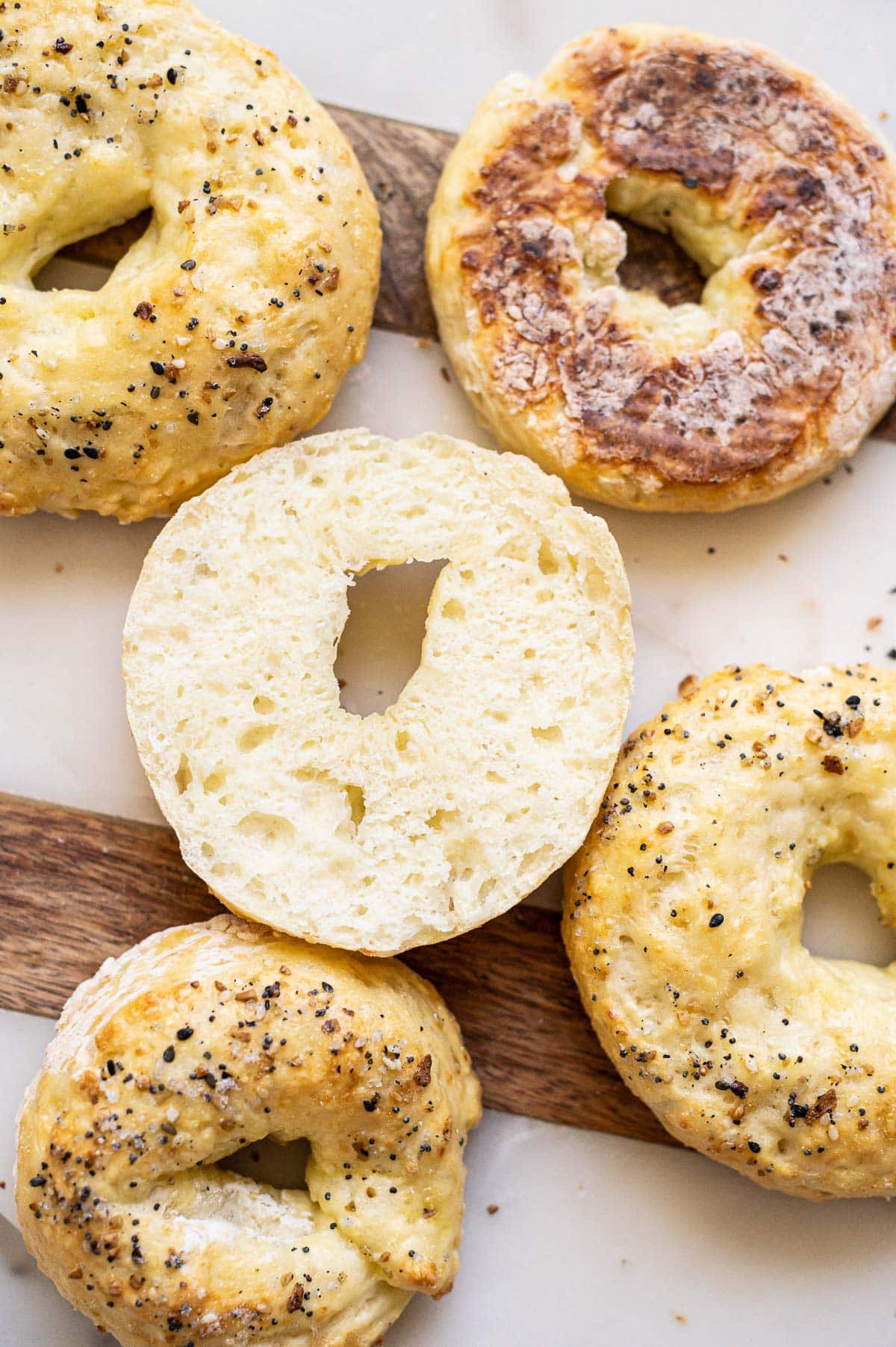 Sliced protein bagel and more bagels around it on a tray.
