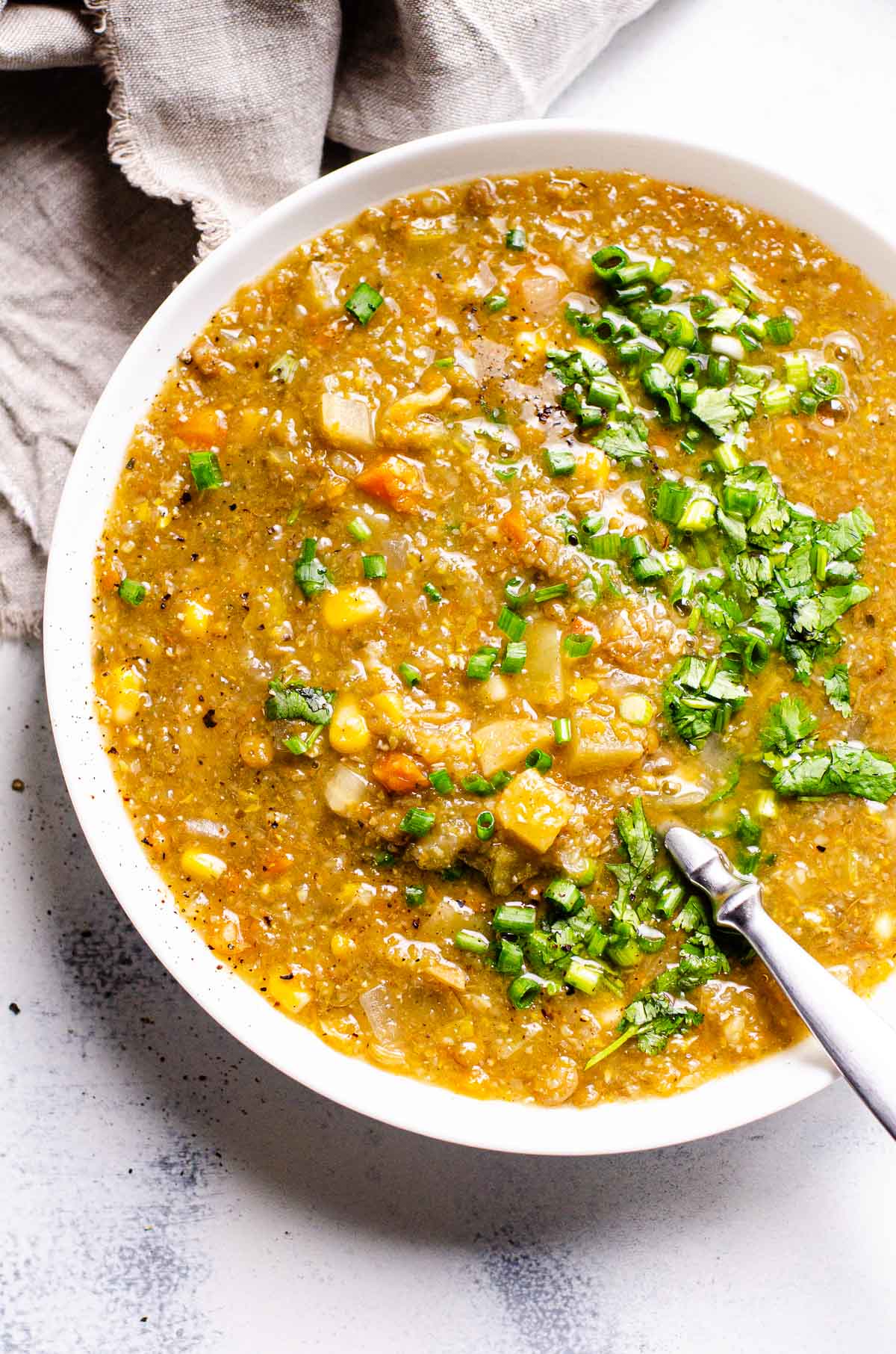 slow cooker lentil soup in large bowl with garnish and spoon for serving
