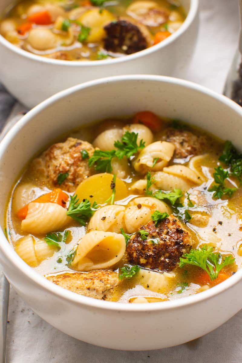 Turkey meatball soup garnished with parsley and pepper and served in white bowls.