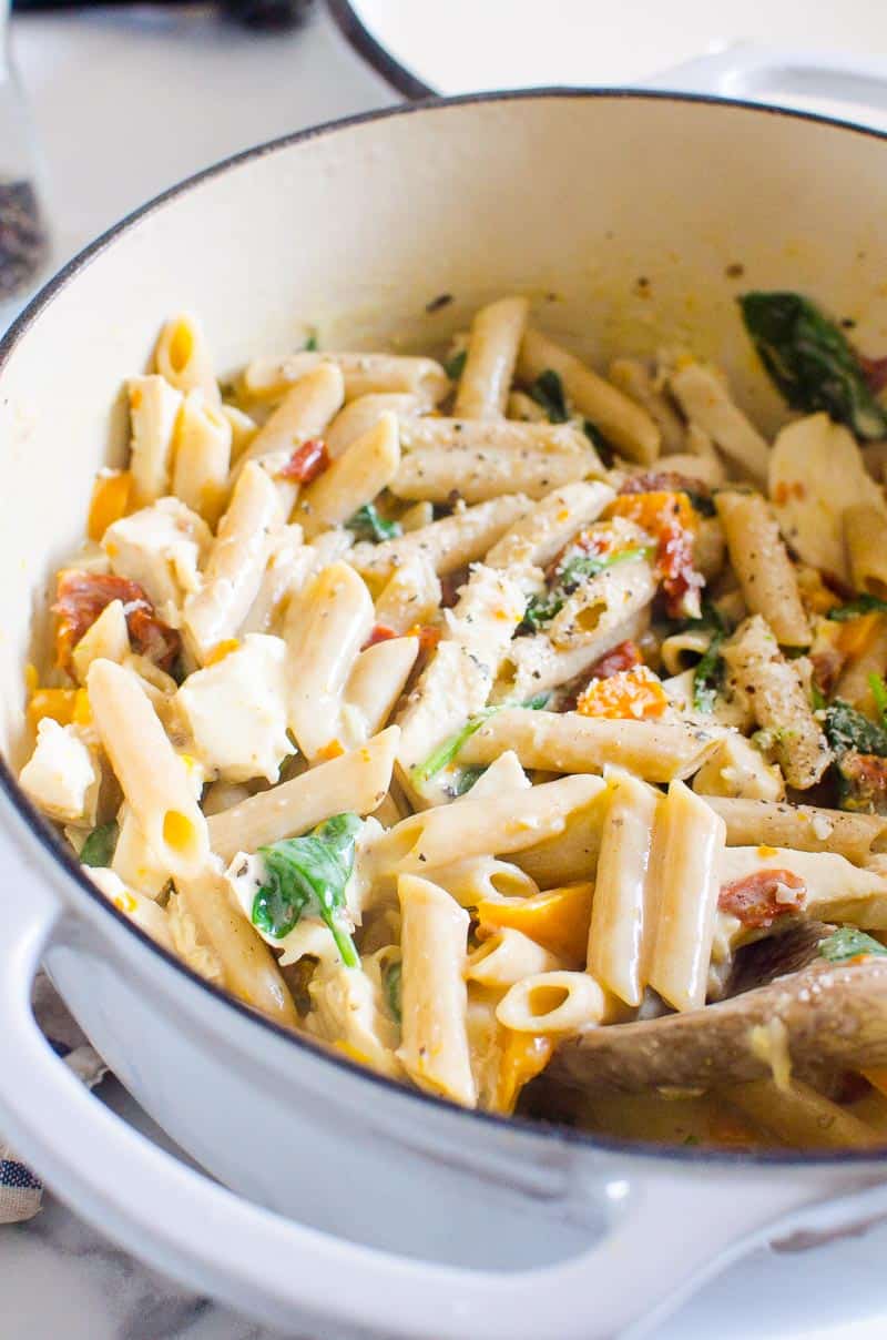 Healthy Tuscan chicken pasta garnished with parmesan cheese.