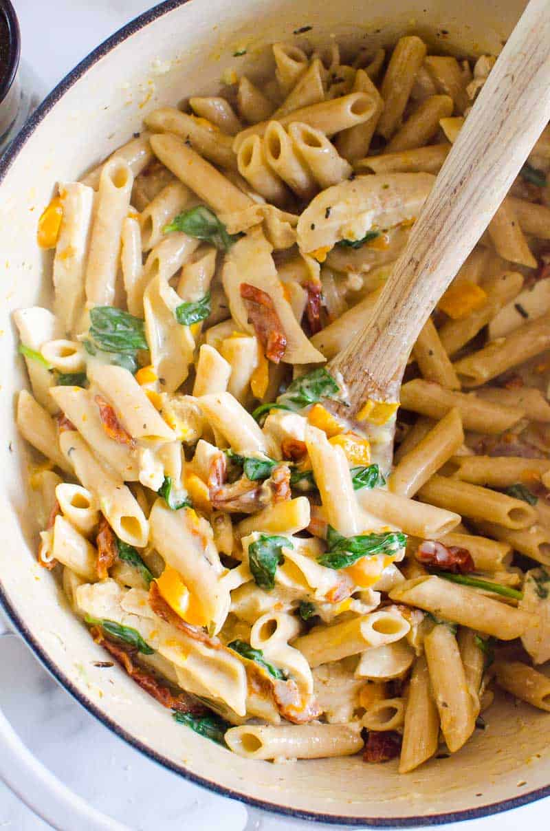 Healthy Tuscan chicken pasta in a pot with serving spoon.