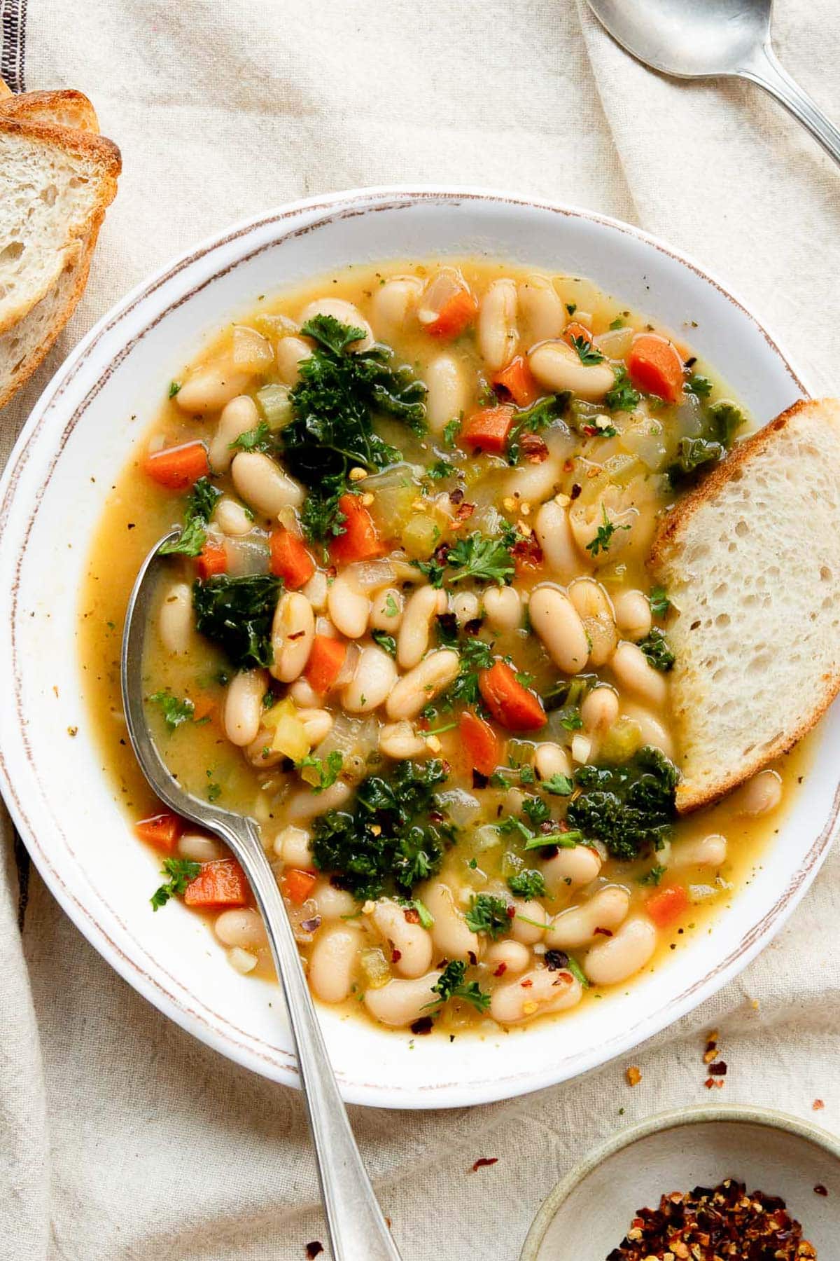 Tuscan white bean soup in a bowl with bread and spoon.
