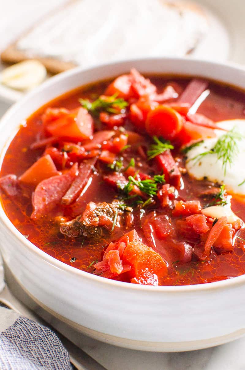 Ukrainian Borscht recipe served in white bowl with sour cream.