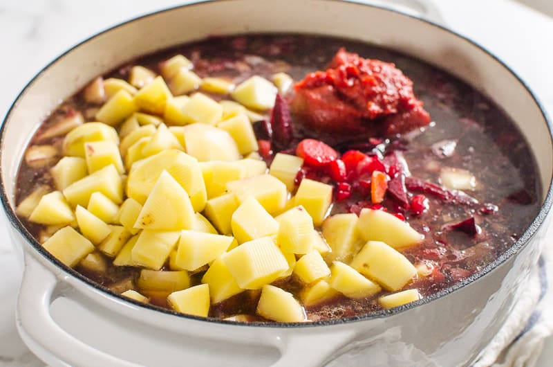 Potatoes, beets, tomato paste and veggies in a pot.