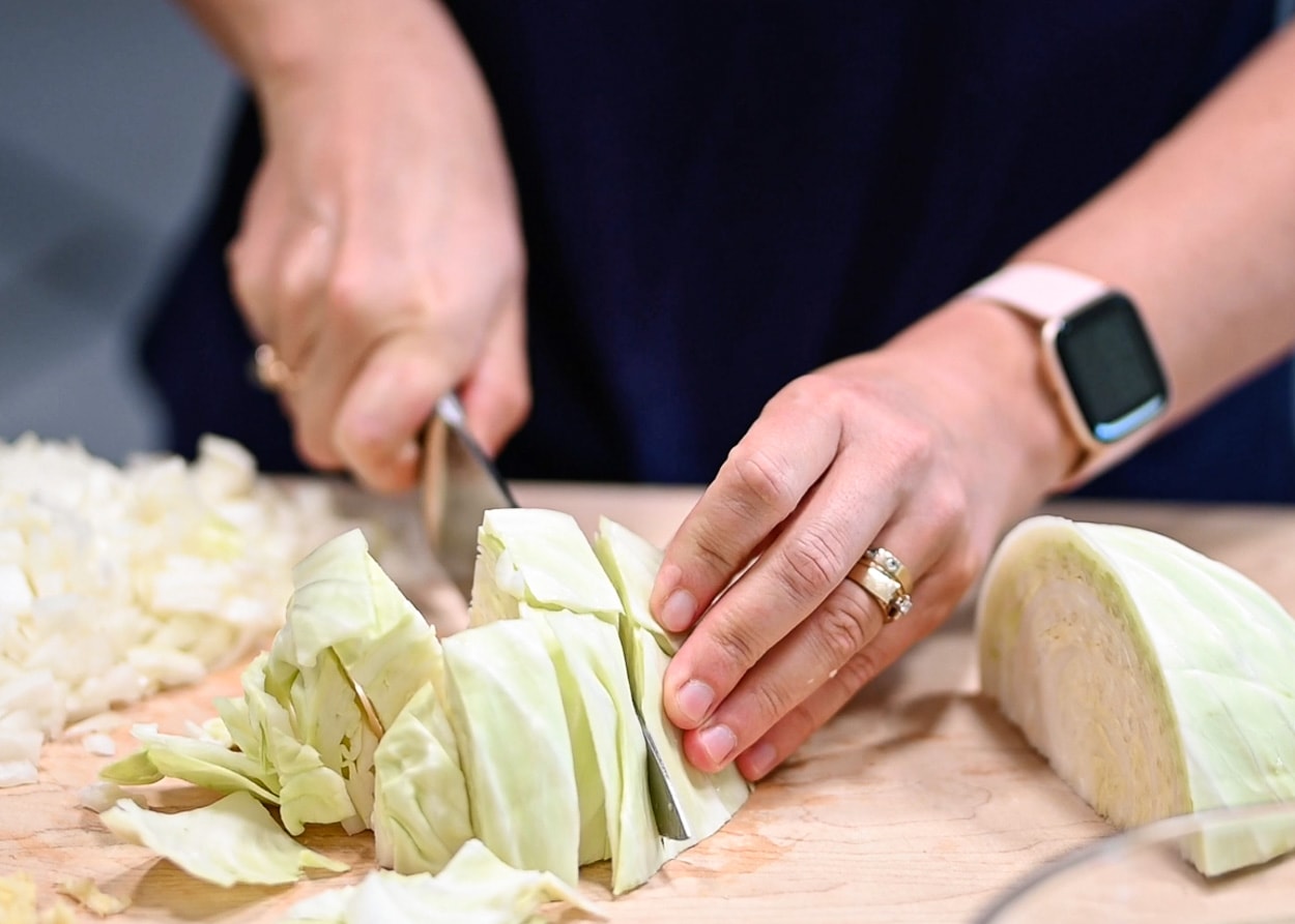 Person chopping the cabbage coarsely.