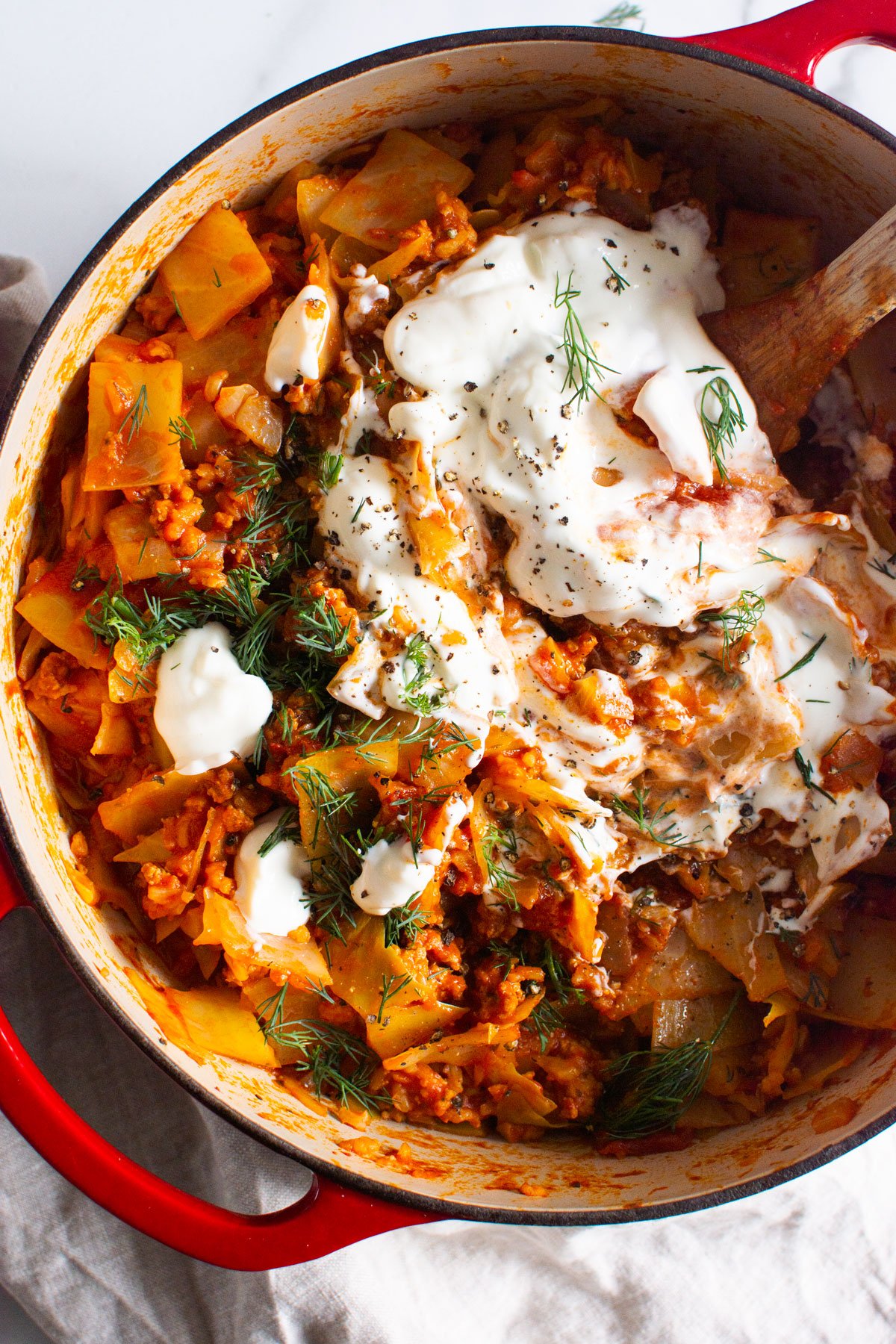 Unstuffed cabbage rolls in red dutch oven with greek yogurt and dill.